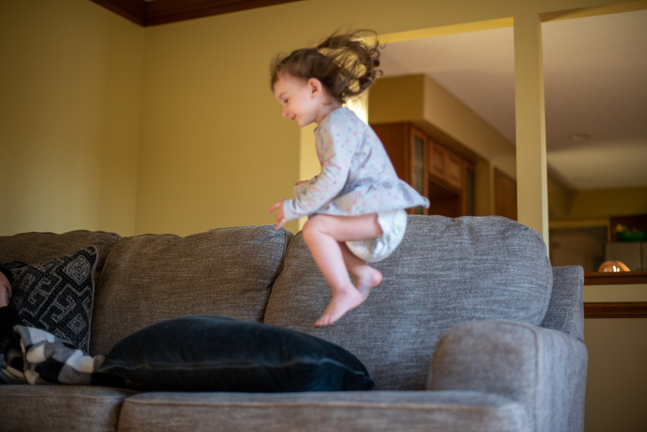 little girl jumping onto couch