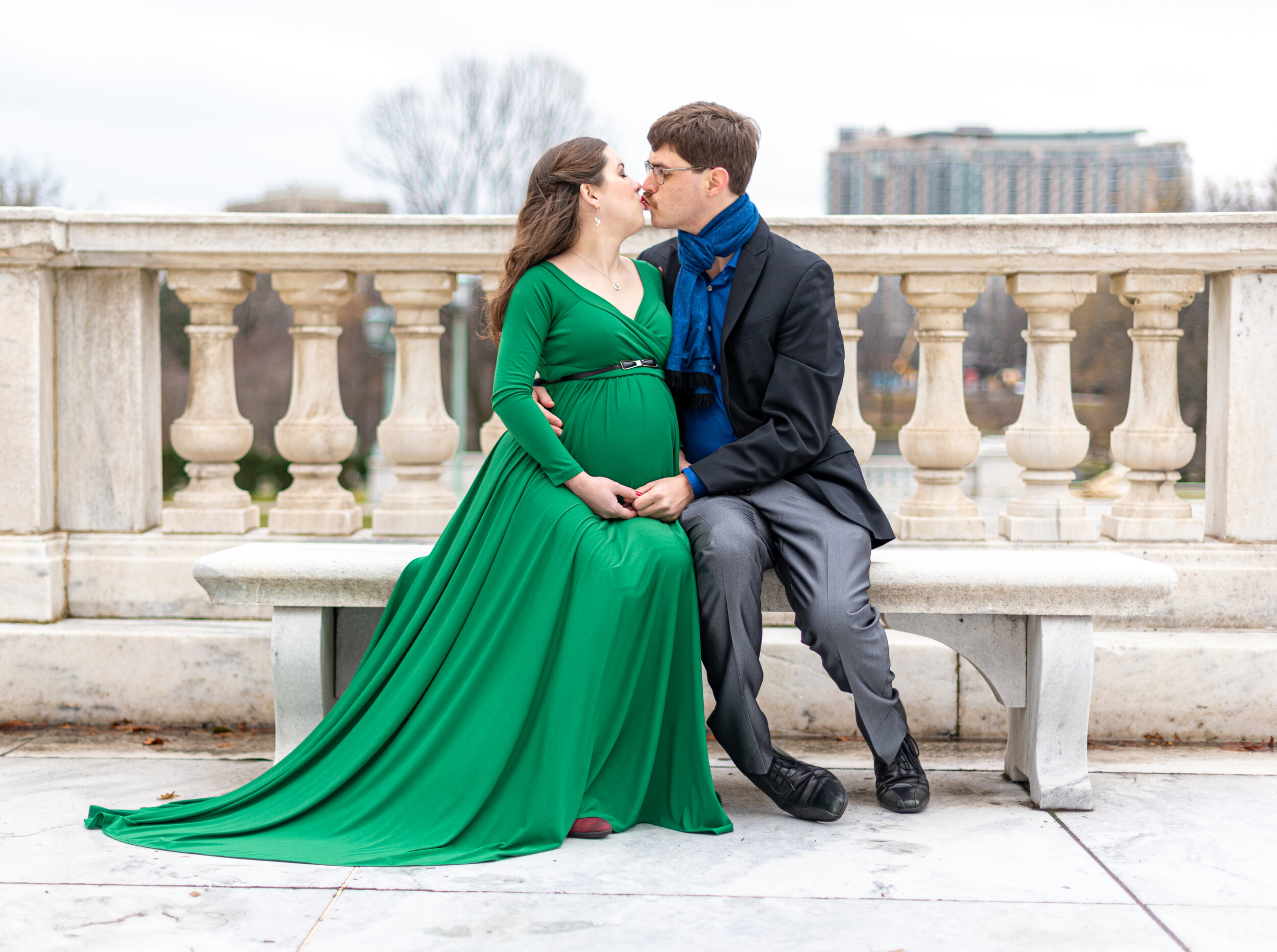 pregnant mother sitting on bench kissing husband at downtown cleveland museum of arts