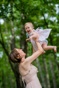 mother throwing daughter in the air outside as she laughs