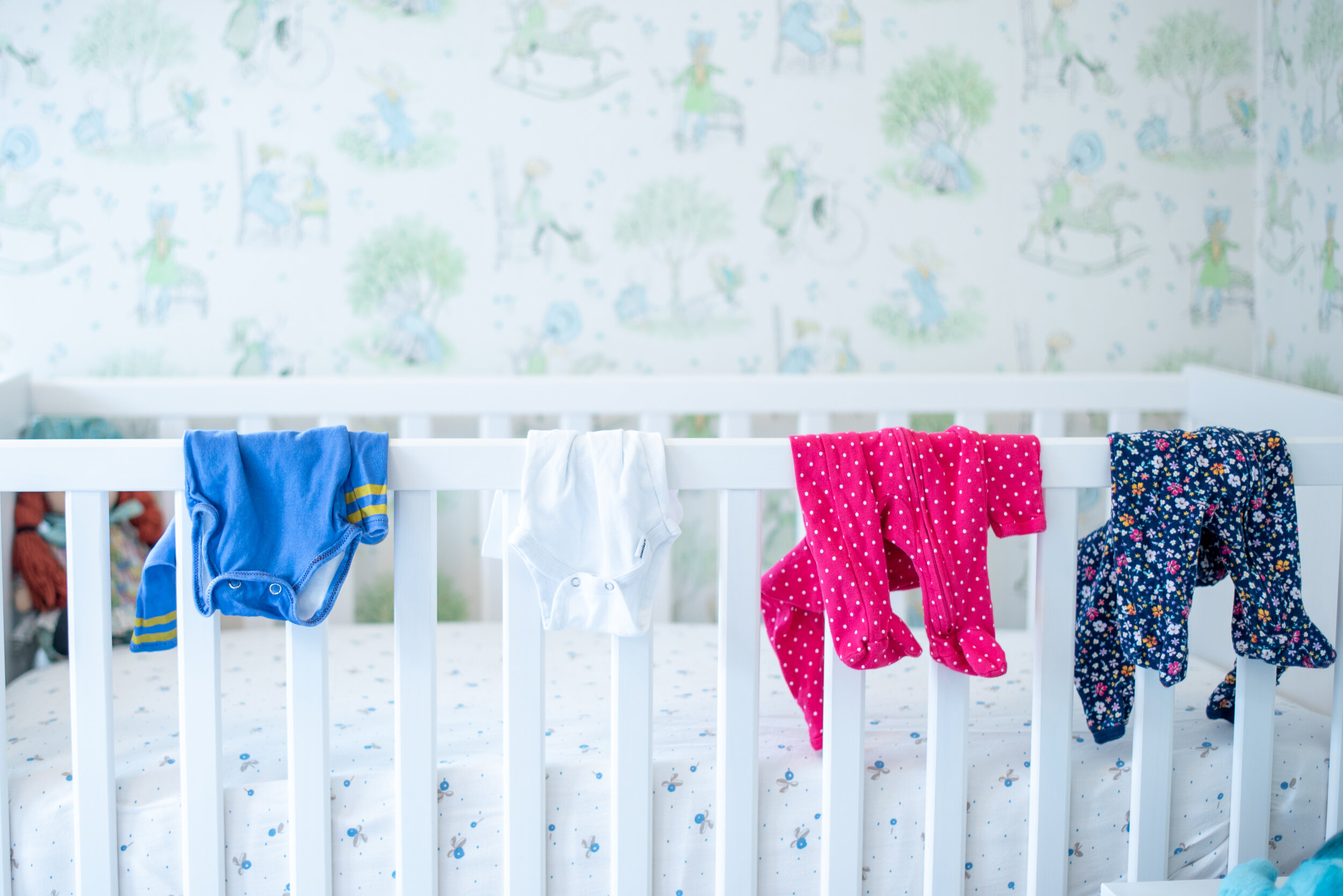 baby clothes hanging over the crib