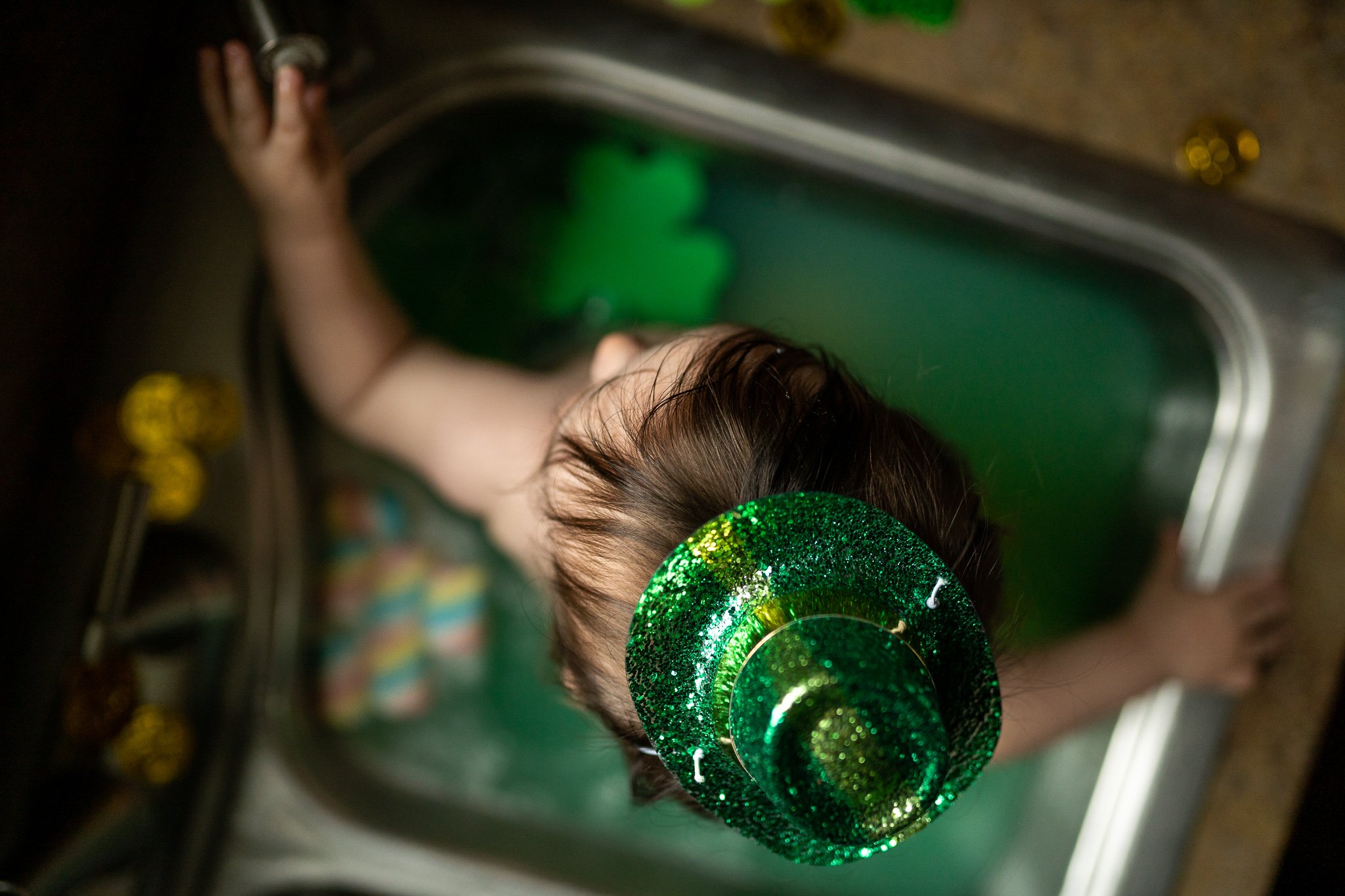 little boy sitting in green tub with green hat on