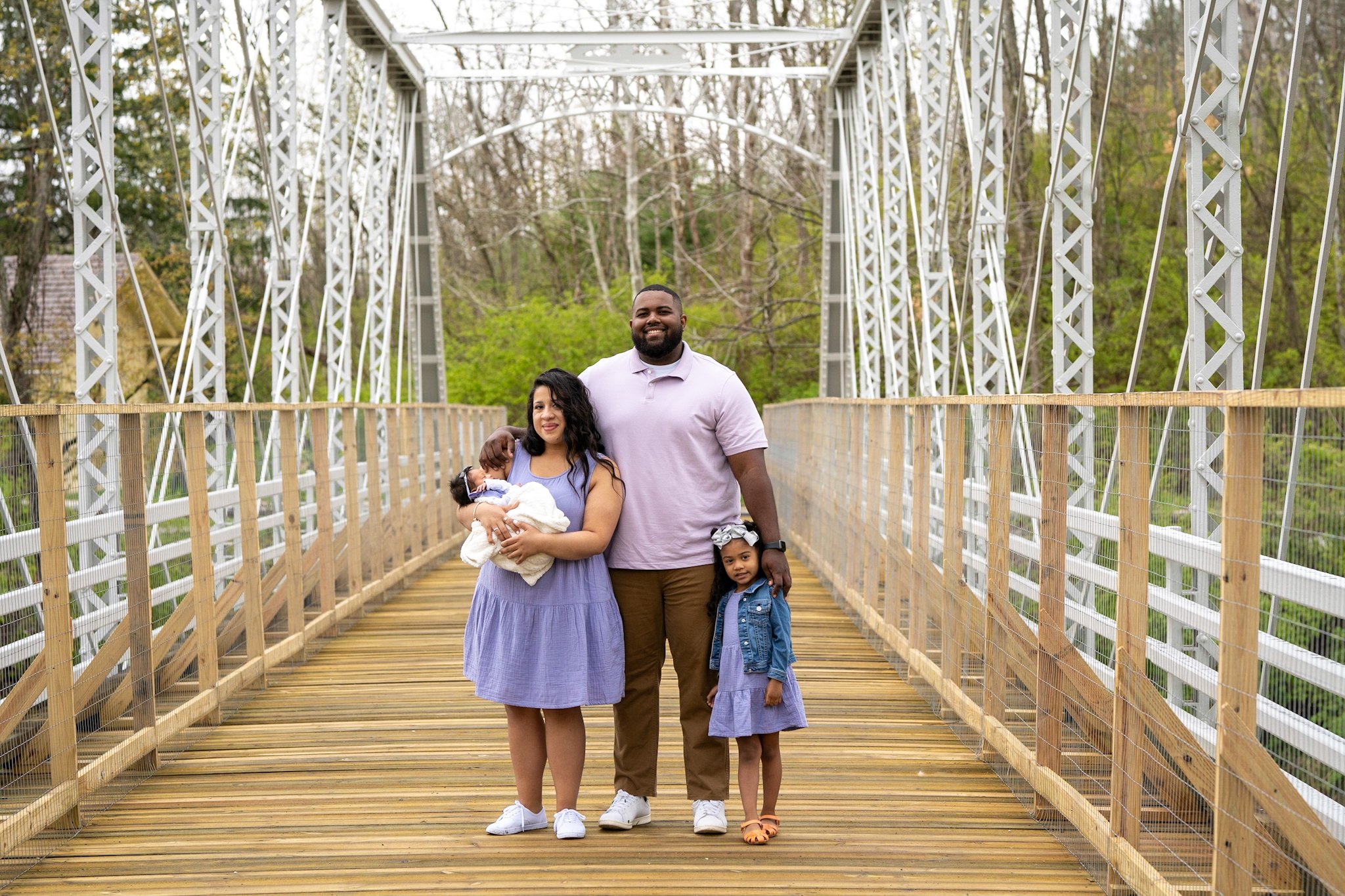 father daughter and mother holding a baby girl standing on a white and wooden bridge at brecksville train station ohio