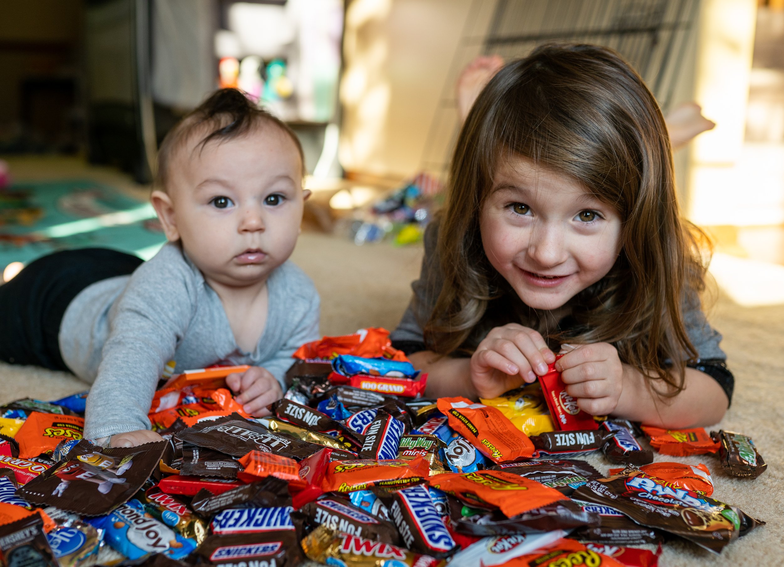brother and sister smiling over a pile of halloween candy