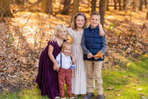 two sisters and two brothers smiling at the camera as the sun sets in the fall foliage in strongsville ohio