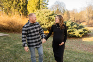 pregnant mother holding husbands' hand and looking at each other while walking towards camera 
