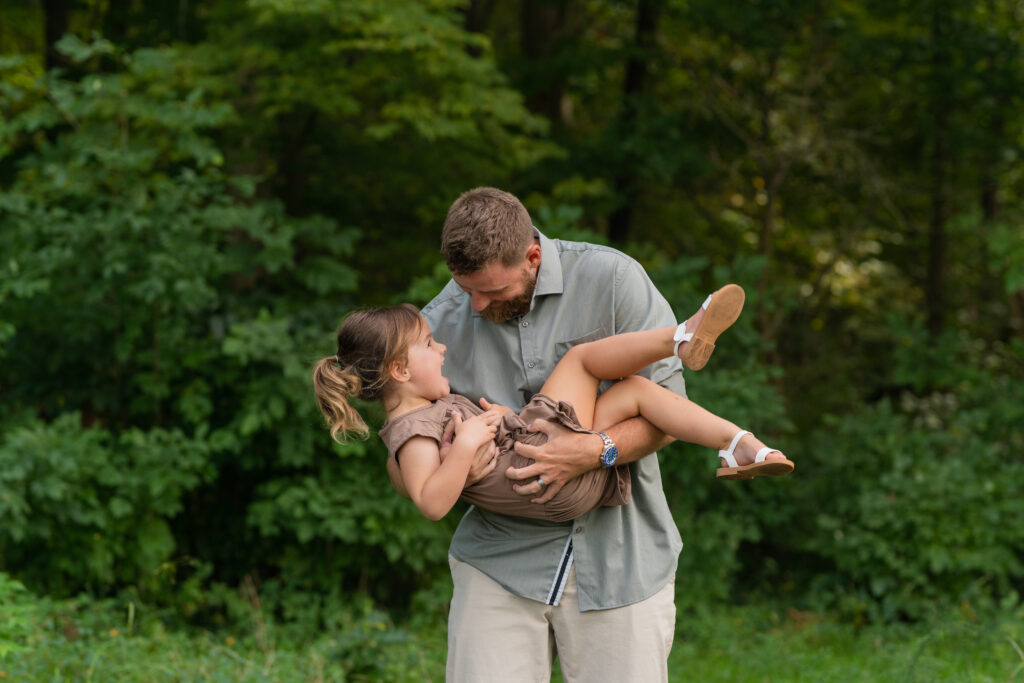 dad holding daughter while tickling her as she laughs at him