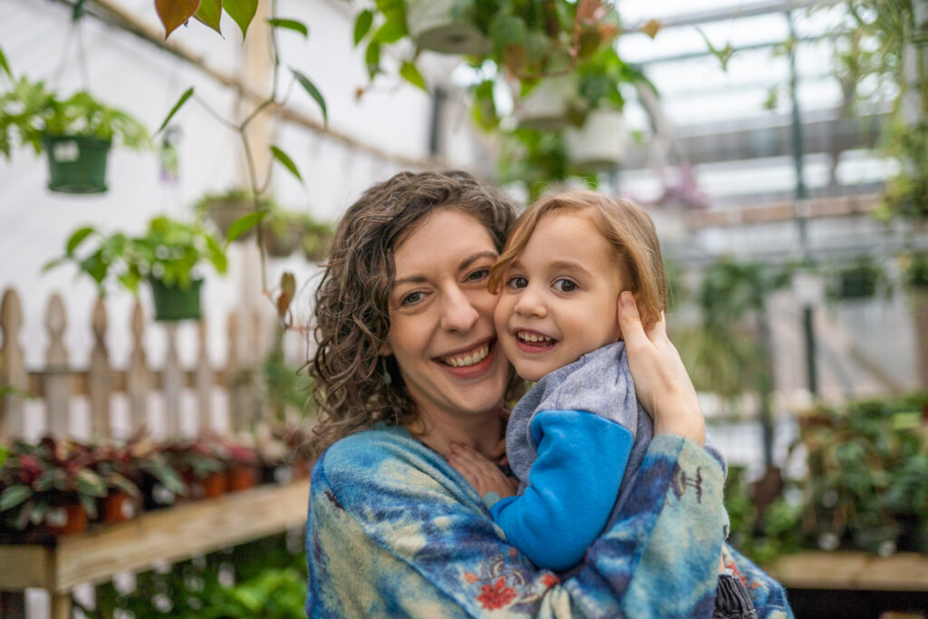 mom holding and hugging son as they both smile at the camera in a north royalton, ohio greenhouse 