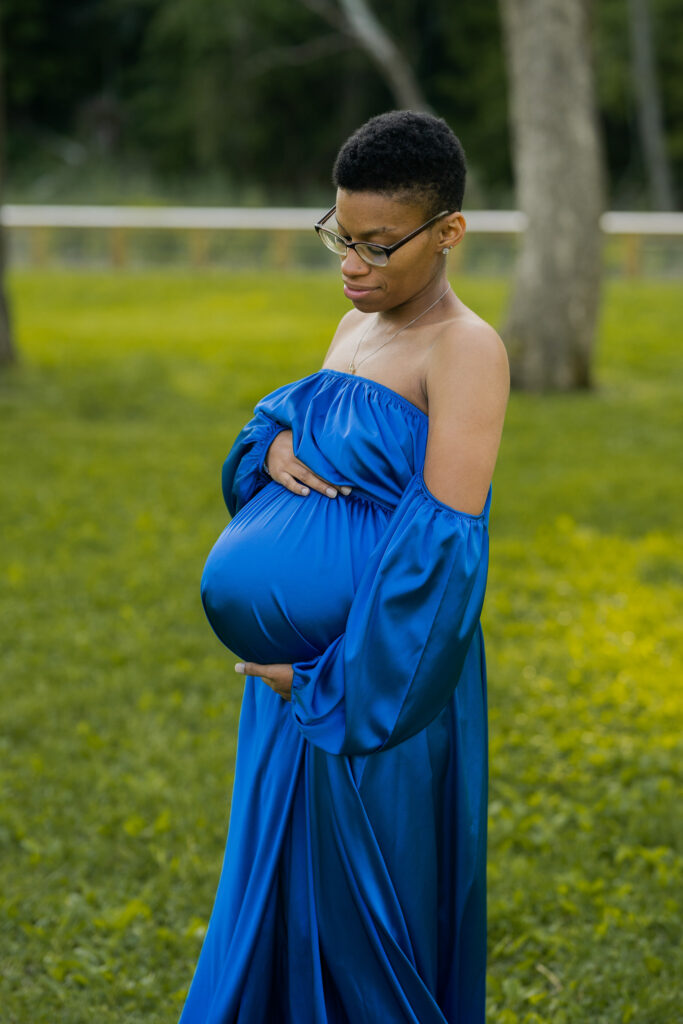 pregnant mother in ocean blue dress holding her belly and looking down at it while smiling in strongsville ohio