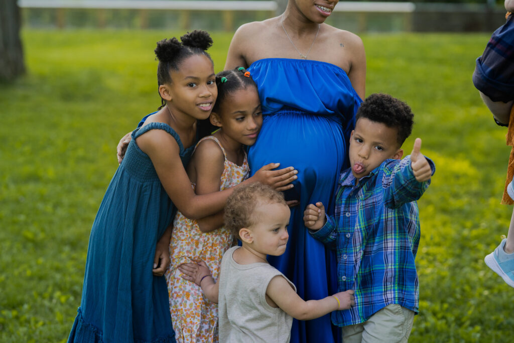 cleveland clinic birthing class and other birthing class instructor angel coleman in cleveland ohio pregnant in a blue dress hugging all of her children